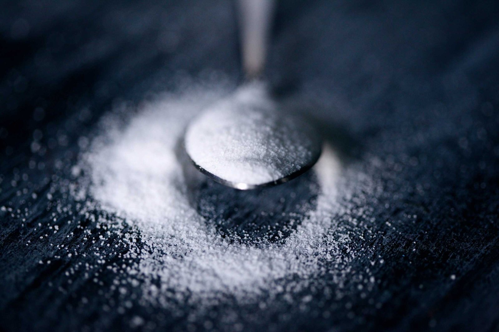 A spoon on a table with sugars all around