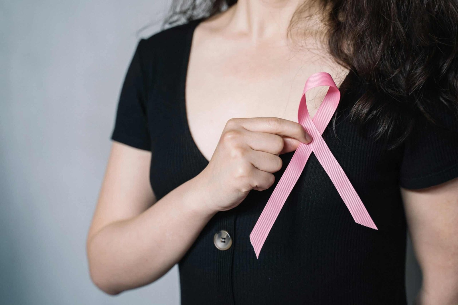 A woman holding a pink ribbon in her hand.