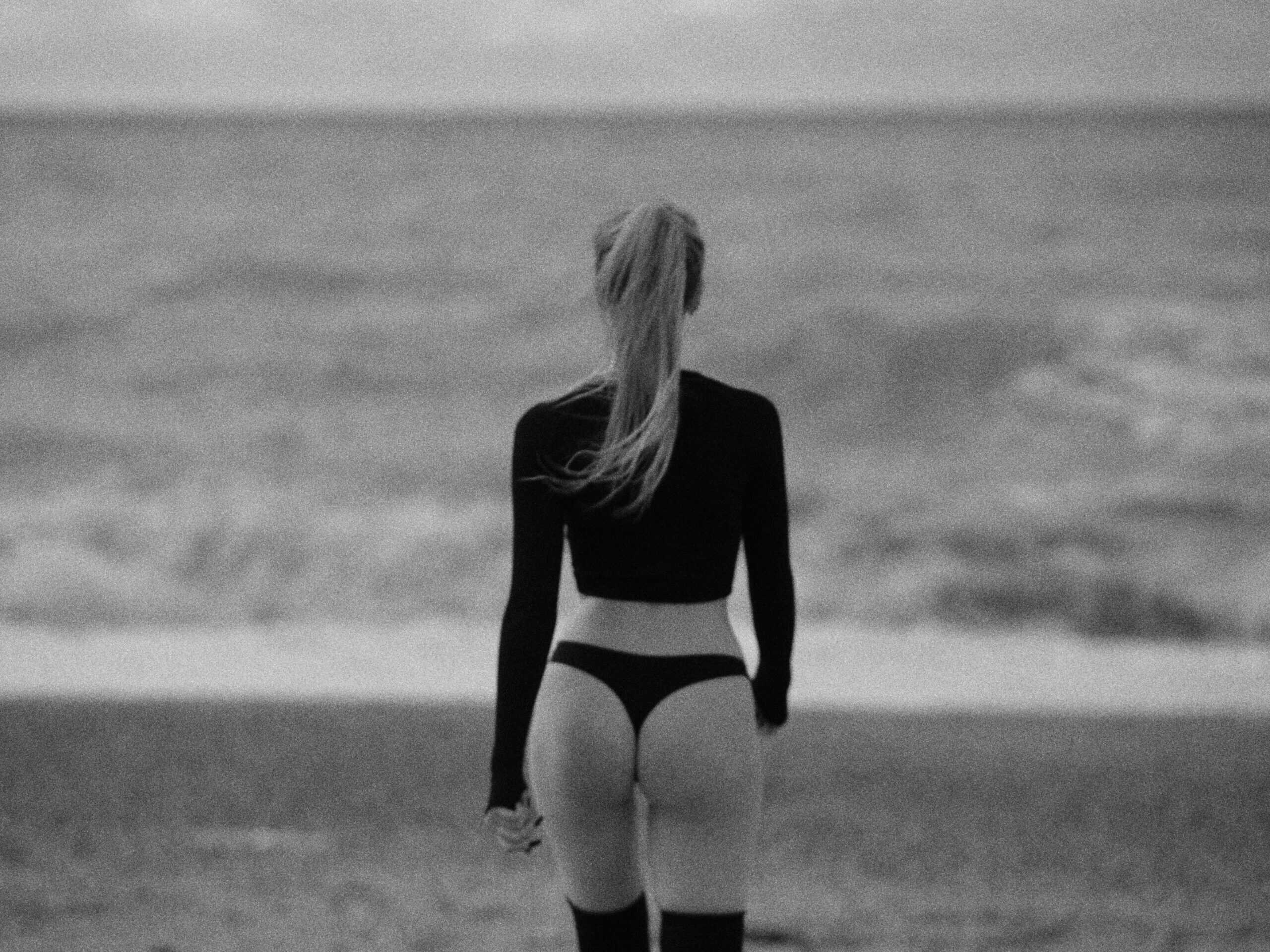 A woman in black and white standing on the beach.