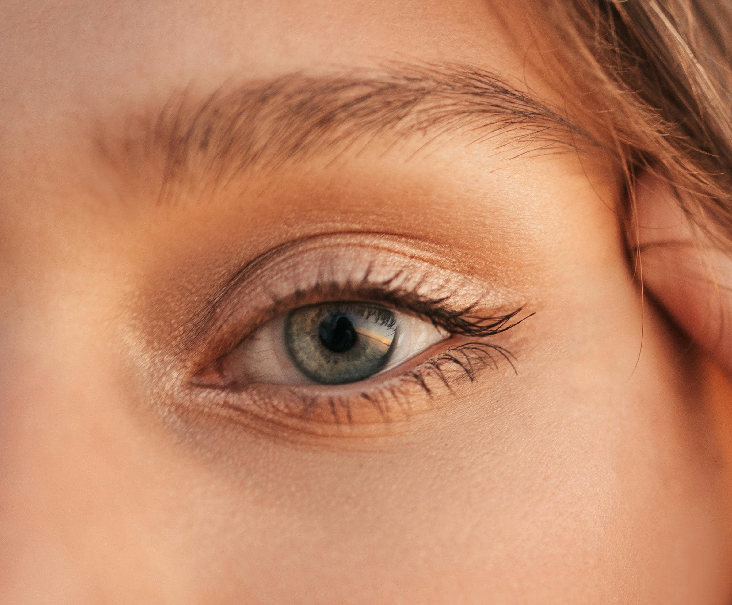 A woman with a green eye and blonde eyebrow