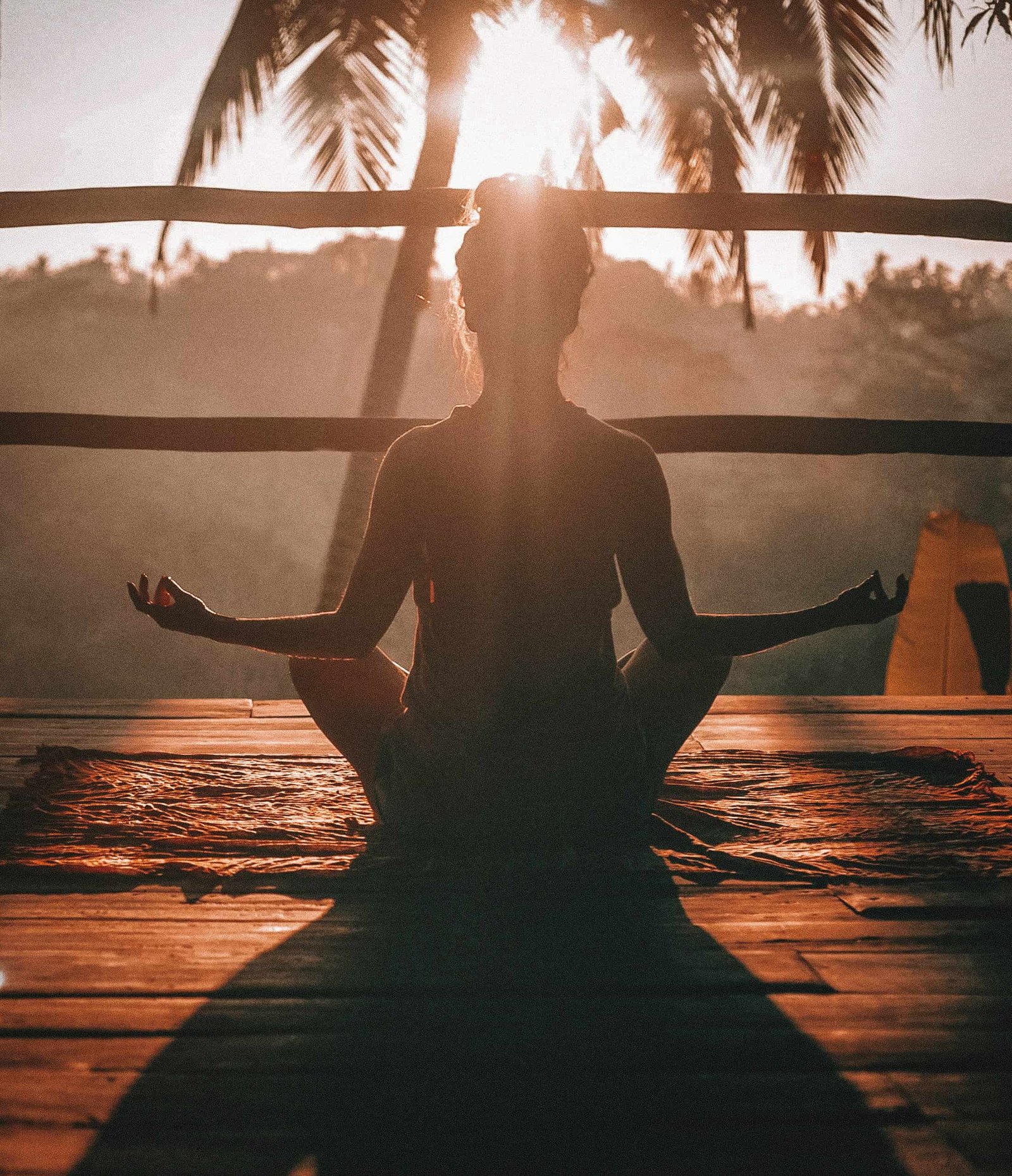 A woman doing Yoga in front of the sun
